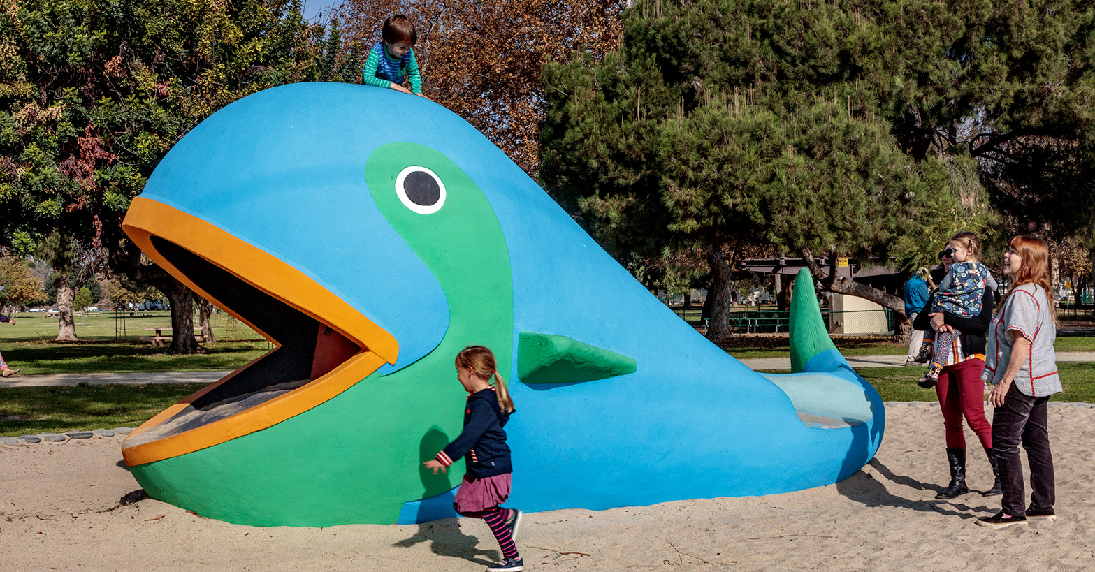 Children play on a giant whale play sculpture