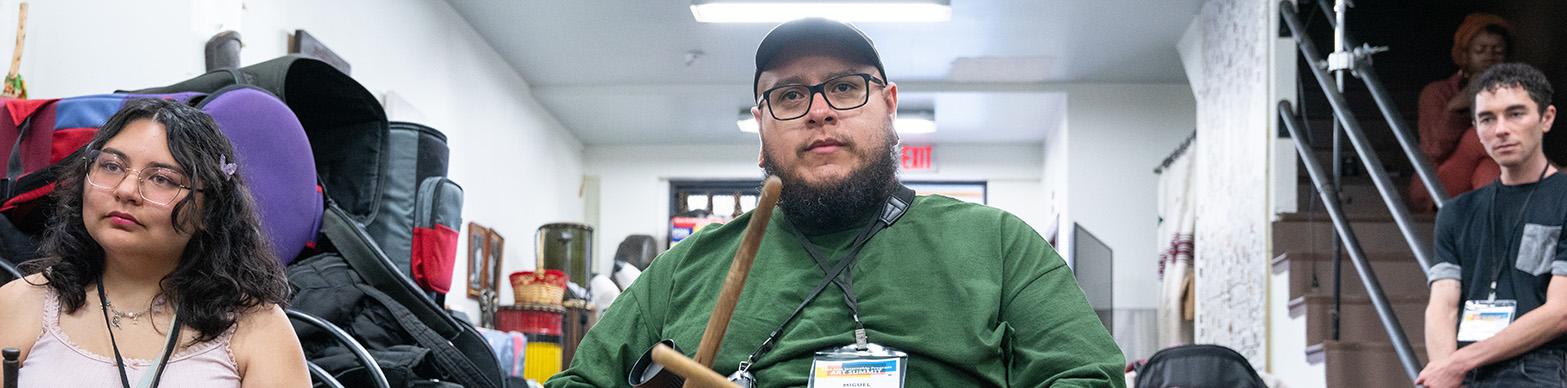 Male intern holds drum sticks, ready to play