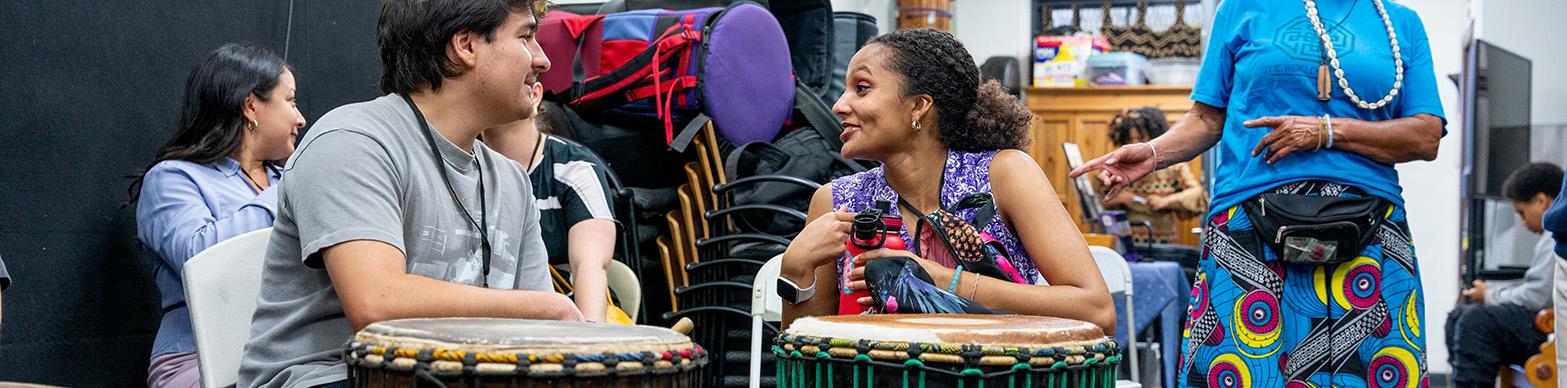 TWo students chat over a pair of drums