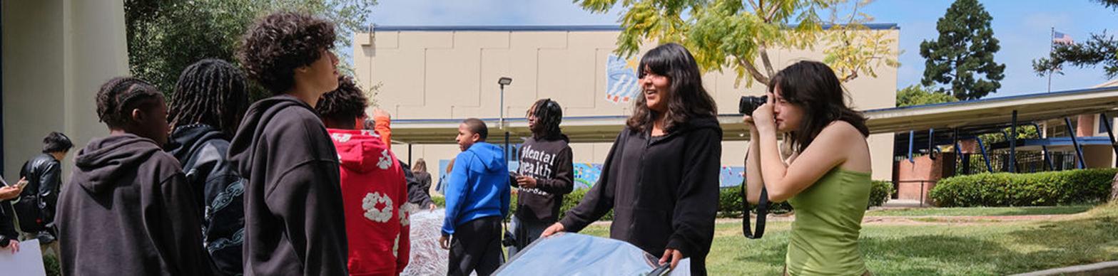 High school aged students running a photo shoot on a green lawn
