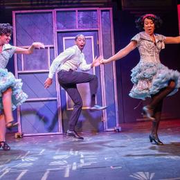 Two black women and one black man dancing on stage