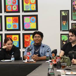 Students speak in front of a wall of art