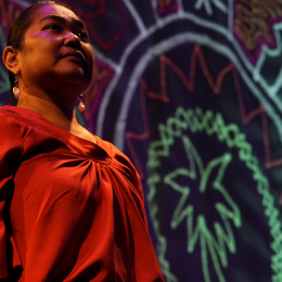 Native woman in front of banner